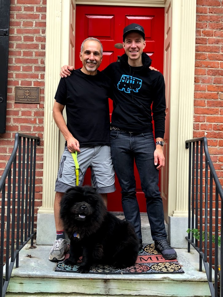 Two men standing in front of a red door

Description automatically generated